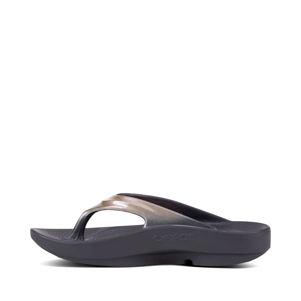 Side (left) view of OOfos OOlala Luxe Flip Sandal for women.